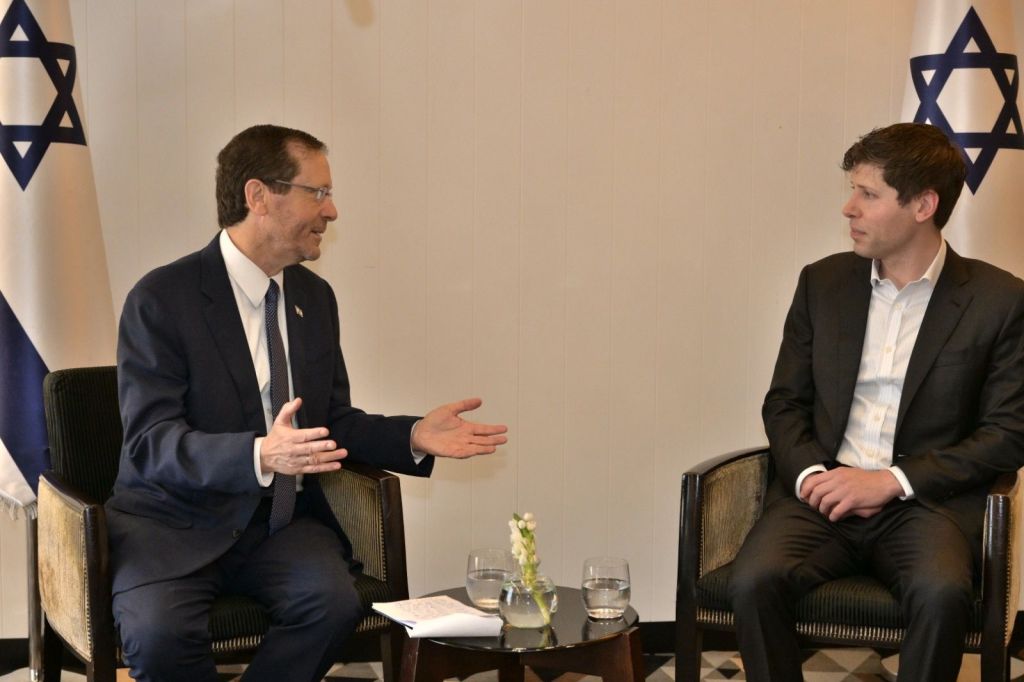 Sam Altman seated across from Isaac Herzog during a meeting, with other participants in the room.