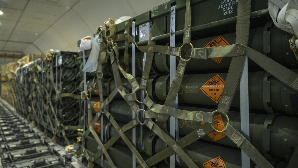 Airmen secure pallets of ammunition inside the cargo hold of an aircraft.
