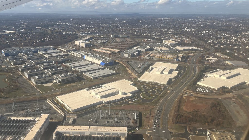Aerial view of large, low data center buildings surrounded by roads and parking lots.