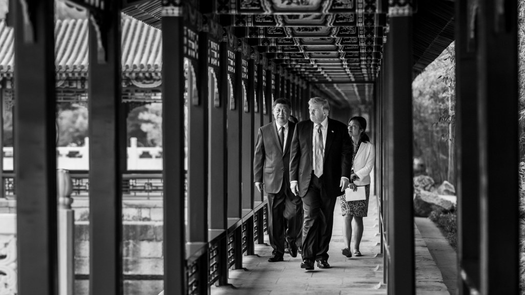 Donald Trump and Xi Jinping walk together outdoors in a traditional Chinese garden setting.