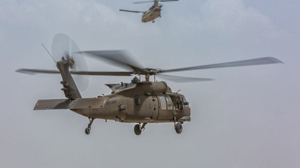 Two U.S. Army helicopters lifting off from an airfield in Erbil, Iraq.