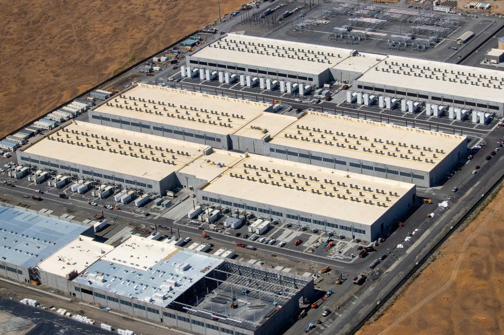Exterior of a large Amazon AWS data center building with parking lot and landscaping in Oregon.